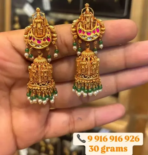 Lakshmi chandbali jhumkas with green bead drops, held at the counter.