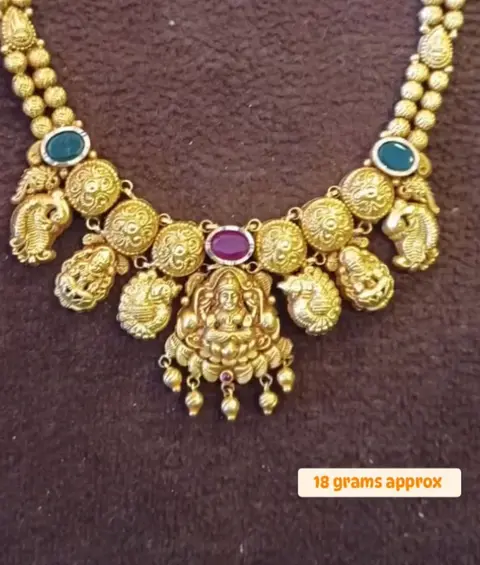 A kemp stone Lakshmi necklace on brown velvet.